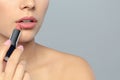 Young woman applying lipstick on color background, closeup. Royalty Free Stock Photo