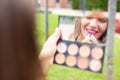 Young woman applying lipstick in mirror at outdoors Royalty Free Stock Photo