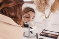 Young woman applying make-up to her face, looking at the round mirror Royalty Free Stock Photo