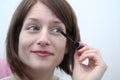 Young woman applying mascara in front of a mirror Royalty Free Stock Photo