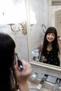 Young woman applying mascara in front of a mirror. Girl getting ready with her makeup in a hotel bathroom. Pretty female smiling Royalty Free Stock Photo