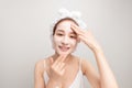 Young woman applying moisturizer cream on her face. Photo of smiling woman receiving spa treatments. Grooming himself Royalty Free Stock Photo