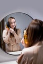 Young woman applying natural organic essential oil on hair and skin. Home spa and beauty rituals. Skin care