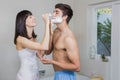 Young woman applying shaving cream on young mans face Royalty Free Stock Photo