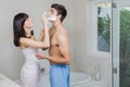 Young woman applying shaving cream on young mans face Royalty Free Stock Photo