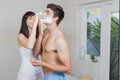 Young woman applying shaving cream on young mans face Royalty Free Stock Photo