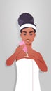 Young woman applying skin cream dressed in towel african american girl cleaning and care her body skincare spa facial Royalty Free Stock Photo