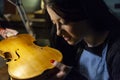 Young woman apprentice violinmaker checking her violin