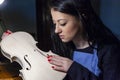 Young woman apprentice violinmaker checking her violin