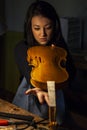 Young woman apprentice violinmaker checking her violin