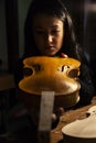 Young woman apprentice violinmaker checking her violin