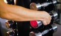 Young woman approaches a dumbbell and takes them to the gym for exercise workout