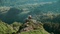 A young woman approaches a man to a cliff in a mountainous area. Travel