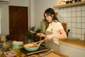 Young woman in apron preparing spaghetti sauce in cozy kitchen Royalty Free Stock Photo