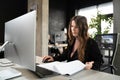 Young woman architect working with blueprints and technical design project at work table and computer in office