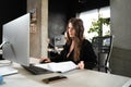 Young woman architect working with blueprints and technical design project at work table and computer in office