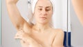 Young woman with armpit hair applying deodorant to remove bad smell and odor. Concept of hygiene, natural beauty, feminity and