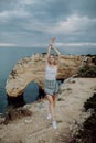 Young woman with arms wide open standing on rock in front of ocean beach on Portugal Royalty Free Stock Photo