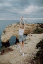 Young woman with arms wide open standing on rock in front of ocean beach on Portugal Royalty Free Stock Photo