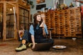 Young woman artist eating sandwich while using laptop in her studio