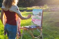 A young woman artist holds a brush and paints a picture on an ea Royalty Free Stock Photo