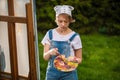 A young woman artist holds a brush and paints a picture on an easel in the rays of the sunset. The painter paints oil paintings in Royalty Free Stock Photo