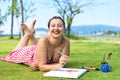 Young woman artist and illustrator drawing witha pencil, laying on a lawn in summer Royalty Free Stock Photo