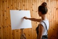 Young woman artist make sketch on canvas on wooden easel.