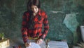 Young woman artist painting scetch on paper notebook with pencil looks in window