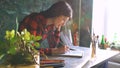 Young woman artist painting sketch on paper notebook with pencil. Bright sun flare from window Royalty Free Stock Photo