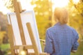 Young woman artist standing near an easel and looking at the sun Royalty Free Stock Photo