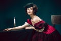 Young woman as Anna Karenina on dark blue background. Retro style, comparison of eras concept.