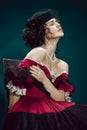 Young woman as Anna Karenina on dark blue background. Retro style, comparison of eras concept.