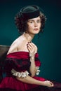 Young woman as Anna Karenina on dark blue background. Retro style, comparison of eras concept.