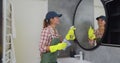 Young woman as a professional cleaner in uniform cleaning bathroom. Cleaning service concept. Royalty Free Stock Photo