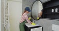 Young woman as a professional cleaner in uniform cleaning bathroom. Cleaning service concept. Royalty Free Stock Photo