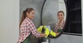 Young woman as a professional cleaner in uniform cleaning bathroom. Cleaning service concept. Royalty Free Stock Photo