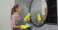 Young woman as a professional cleaner in uniform cleaning bathroom. Cleaning service concept. Royalty Free Stock Photo