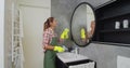 Young woman as a professional cleaner in uniform cleaning bathroom. Cleaning service concept. Royalty Free Stock Photo