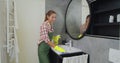 Young woman as a professional cleaner in uniform cleaning bathroom. Cleaning service concept. Royalty Free Stock Photo