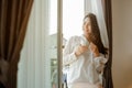 Young woman asia living at home relaxing and drinking cup of hot coffee in the bedroom on holiday. Royalty Free Stock Photo