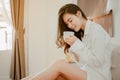 Young woman asia living at home relaxing and drinking cup of hot coffee in the bedroom on holiday. Royalty Free Stock Photo