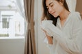 Young woman asia living at home relaxing and drinking cup of hot coffee in the bedroom on holiday. Royalty Free Stock Photo