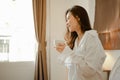 Young woman asia living at home relaxing and drinking cup of hot coffee in the bedroom on holiday. Royalty Free Stock Photo