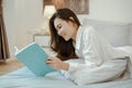 Young woman asia living at home relaxing and reading a book in the bedroom on holiday Royalty Free Stock Photo