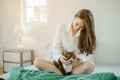 Young woman asia wake up refreshed in the morning playing with cats at bed happily on holiday. Royalty Free Stock Photo