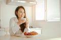 Young woman asia wake up refreshed in the morning and relaxing eat coffee, cornflakes, bread and apple for breakfast at house on h Royalty Free Stock Photo