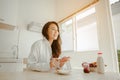 Young woman asia wake up refreshed in the morning and relaxing eat coffee, cornflakes, bread and apple for breakfast at house on h Royalty Free Stock Photo