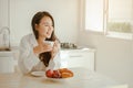 Young woman asia wake up refreshed in the morning and relaxing eat coffee, cornflakes, bread and apple for breakfast at house on h Royalty Free Stock Photo