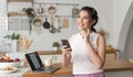 Young woman Asian happy and interested in thinking using mobile phone in kitchen room